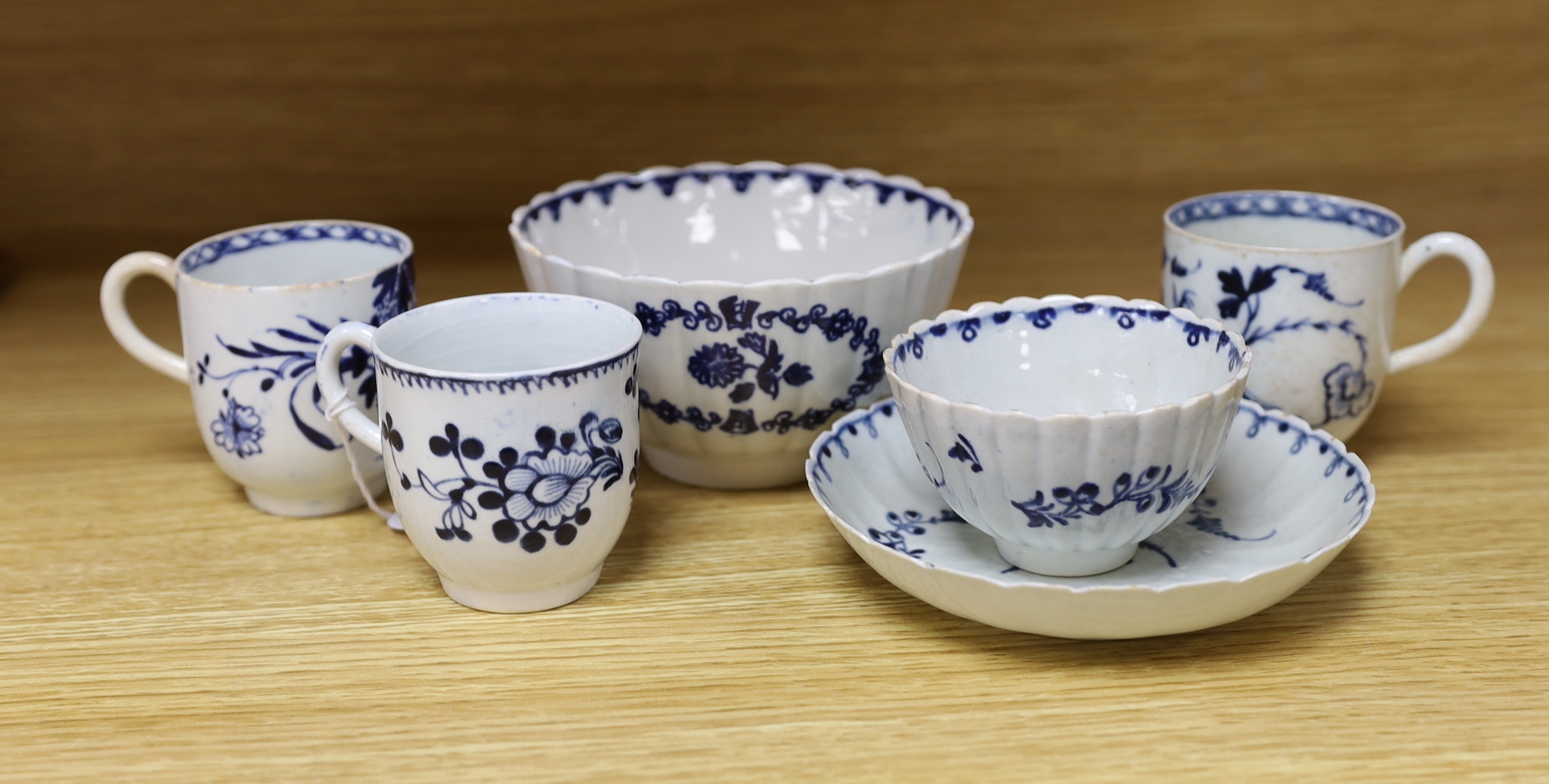 A Liverpool tea bowl and saucer painted with trailing flowers, the saucer with an additional central spray, on a fluted body, similar bowl painted with flowers in three wreath panels, a coffee cup painted with flowers an